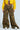 A person wearing a yellow jacket and wide-leg, high-rise HIDDEN IN PLAIN SIGHT CARGO PANT stands against a plain background. These camo print pants feature large pockets and are paired with sleek white sneakers.