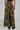 Someone is wearing the RIDE WITH ME CAMO WIDE LEG PANT, featuring high-rise and cargo-style pockets, paired with black platform shoes. The green and brown camouflage pattern stands out from the back view.