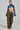 A person poses confidently against a light background, wearing a blue cropped top with colorful sleeve text and RIDE WITH ME CAMO WIDE LEG PANT featuring cargo pockets. They complete the outfit with bright red shoes and have a high ponytail.