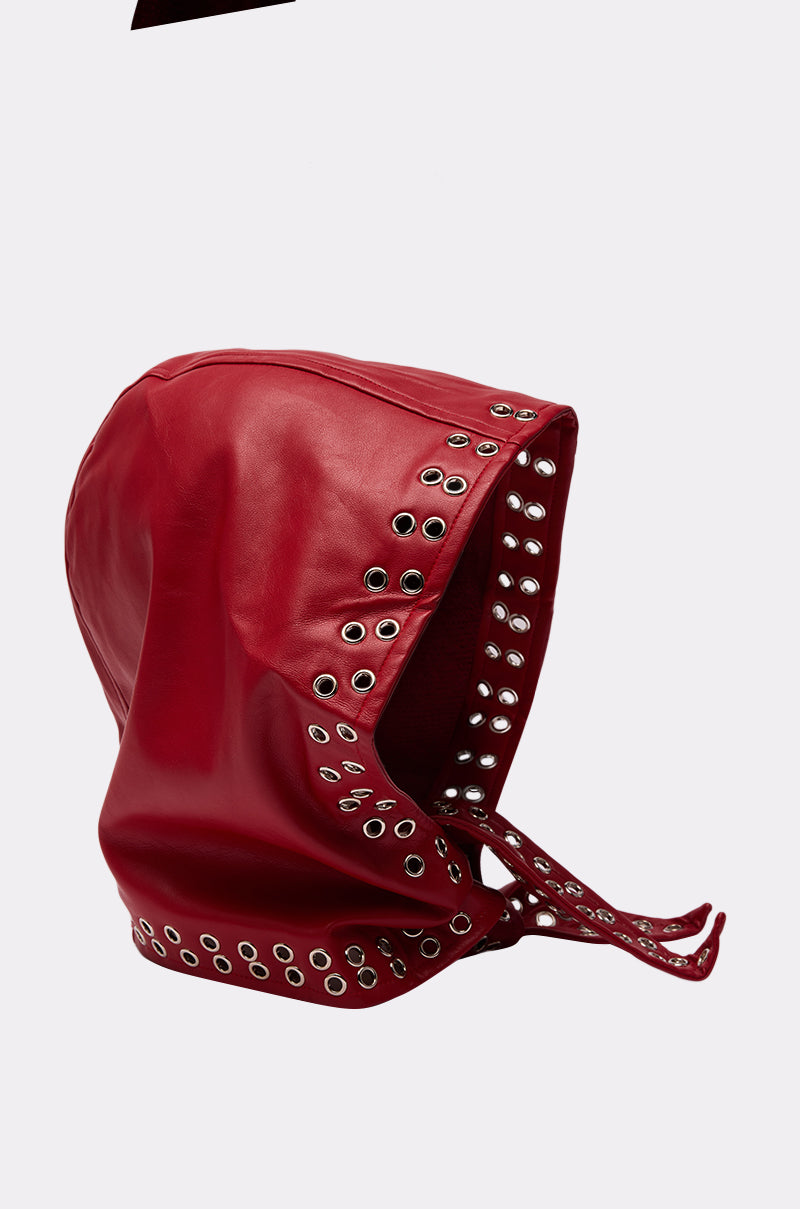 The BUCKLE UP PU HEADSCARF is a bold red faux leather accessory with silver eyelets along the edges and two front straps, shown against a plain light gray background. 5