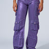 Person wearing THE POWER OF LOVE DENIM CARGO PANT in high-rise wide-leg purple, featuring multiple pockets, paired with metallic silver sneakers, standing against a plain background. Their face is not visible in the image.