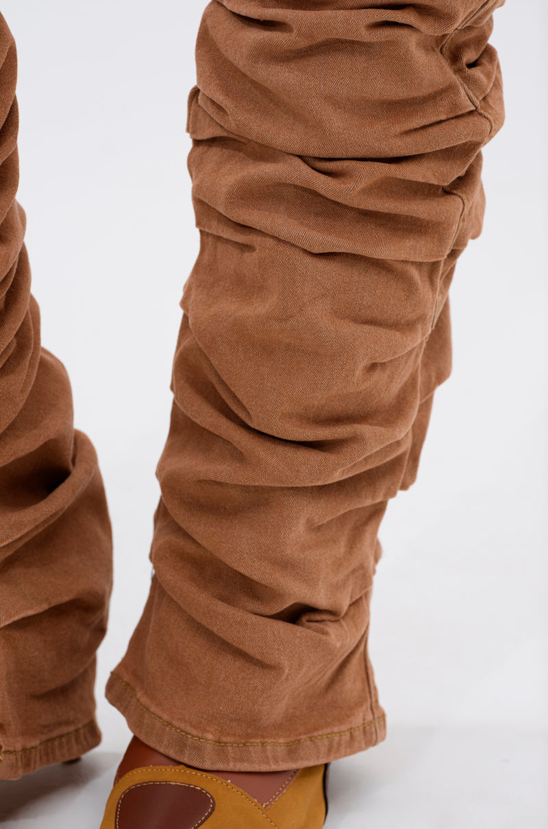 A close-up of the IT GETS EASIER STACKED CARGO PANT IN MOCHA, featuring ruched detailing at the lower legs, styled with brown and tan shoes against a plain light background. 6