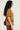Wearing a Freedom Oversized Tee in a grunge style, a person with long curly hair and sunglasses stands in profile. Their bold red pants are complemented by the gold metallic chain link accenting the black bag over their shoulder.