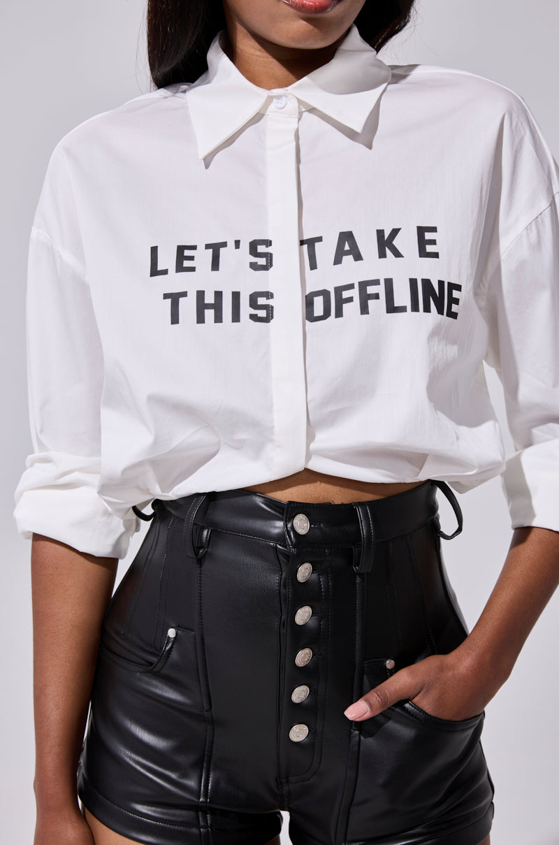 A person wearing the LETS TAKE IT OFFLINE BUTTON DOWN white shirt and high-waisted black leather shorts with buttons, standing confidently with one hand in a pocket. 8