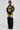 Confidently sporting the MADE EXTREME OVERSIZED BOMBER with black and yellow colorblock paneling and a bold "M" logo, the look is paired with fuzzy black leg warmers for a fashion-forward, sports-inspired style against a plain background.