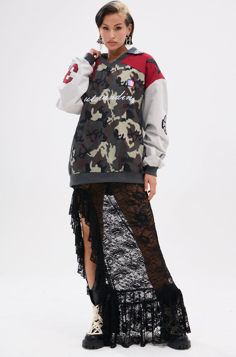 A person wears the FLIP THE SWITCH PATCHWORK DETAILED JERSEY TOP with a black lace asymmetrical skirt and beige combat boots, posing against a plain white background.