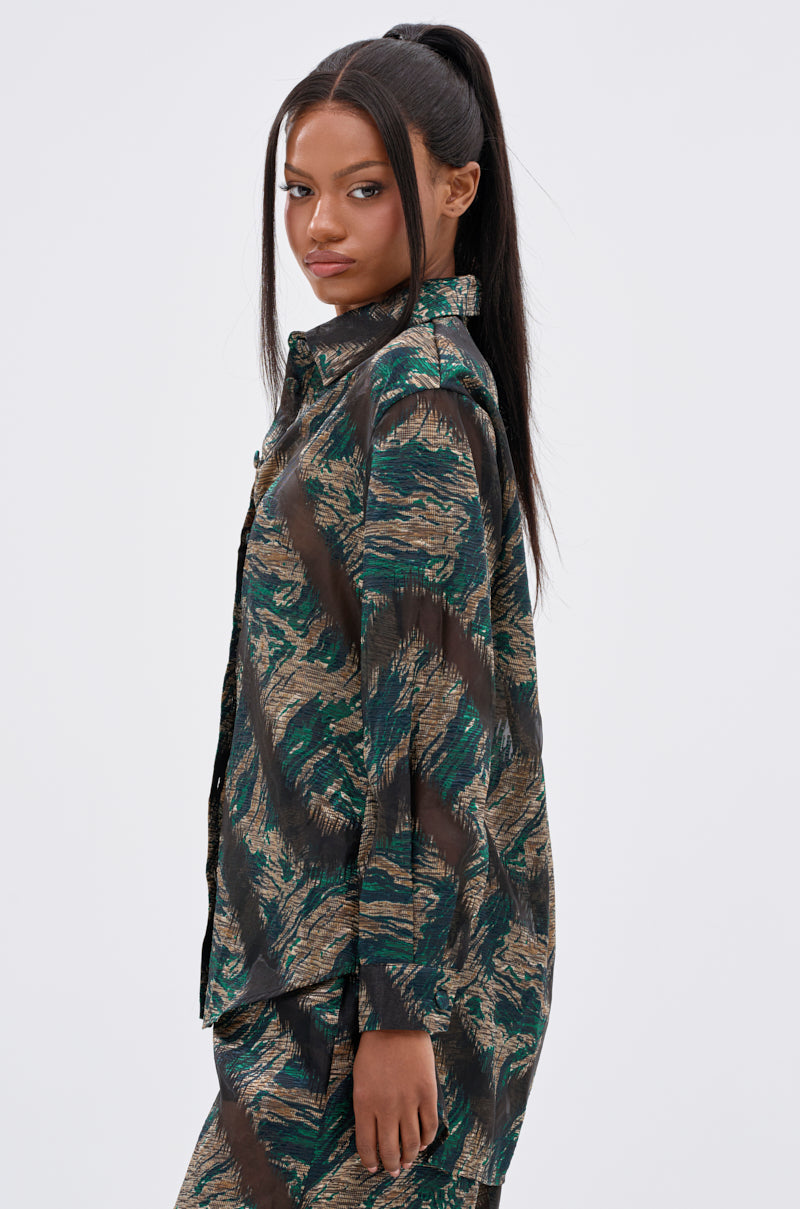 A woman with long, straight black hair in a high ponytail wears the IN TOO DEEP BUTTON DOWN TOP and matching pants, standing sideways and looking over her shoulder against a plain light background.