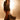 A woman stands confidently in dramatic lighting, wearing the CHLOE MESH FLARE MAXI SKIRT with a black blazer, lace-up boots, and a small round purse. Her wavy brown hair and bold look exude high-fashion style.