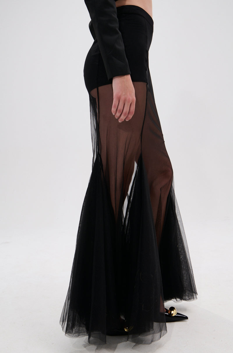 A person wearing the CHLOE MESH FLARE MAXI SKIRT with a high-rise waist and black flat shoes stands sideways against a plain white background.