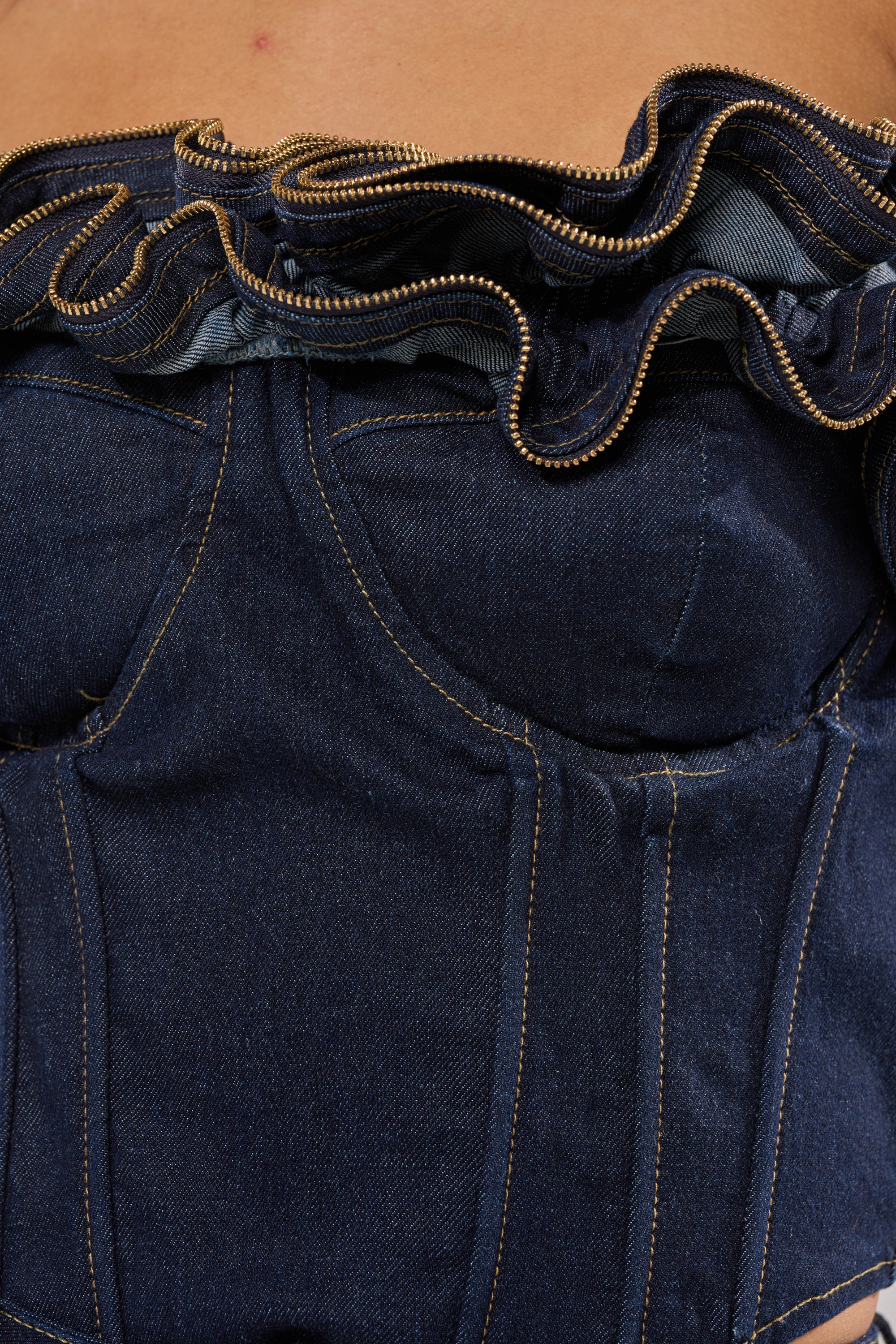 Close-up of a person wearing the SOMETHING DIFFERENT DENIM CORSET WITH ZIPPER DETAIL, featuring visible stitching and a zipper accentuating the ruffled neckline.