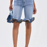 Wearing the LONDON BERMUDA SHORT in light blue with ruffled hems, paired with a matching blue handbag and blue fringe slide sandals. The upper body is not visible.