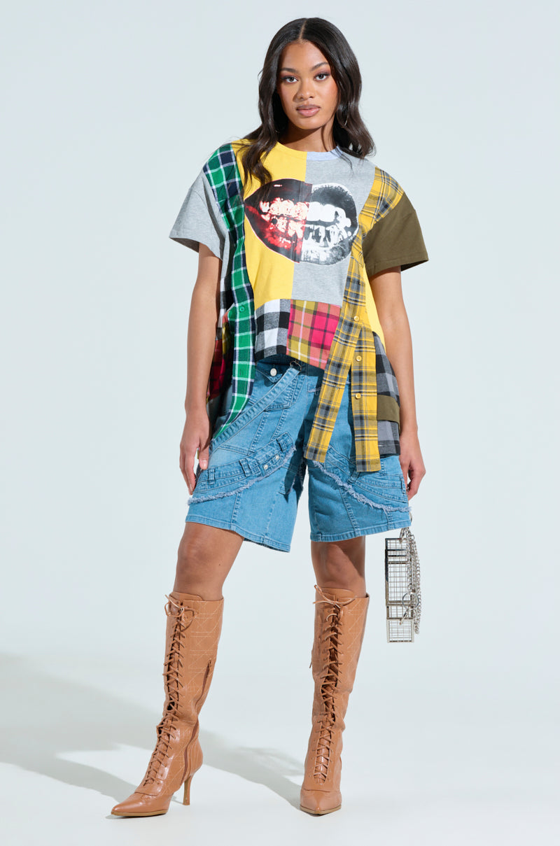 A woman poses in a patchwork t-shirt, paired with GRAB ME CLOSER DENIM BERMUDA SHORTS and tan lace-up knee-high boots. She holds a small cage-like handbag against a light background.
