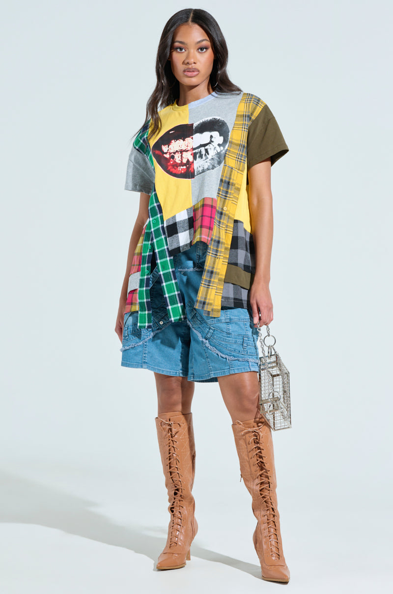 Dressed in a colorful patchwork T-shirt and GRAB ME CLOSER DENIM BERMUDA SHORTS, they pair the look with tan lace-up knee-high boots, holding a small metallic handbag against a plain background.
