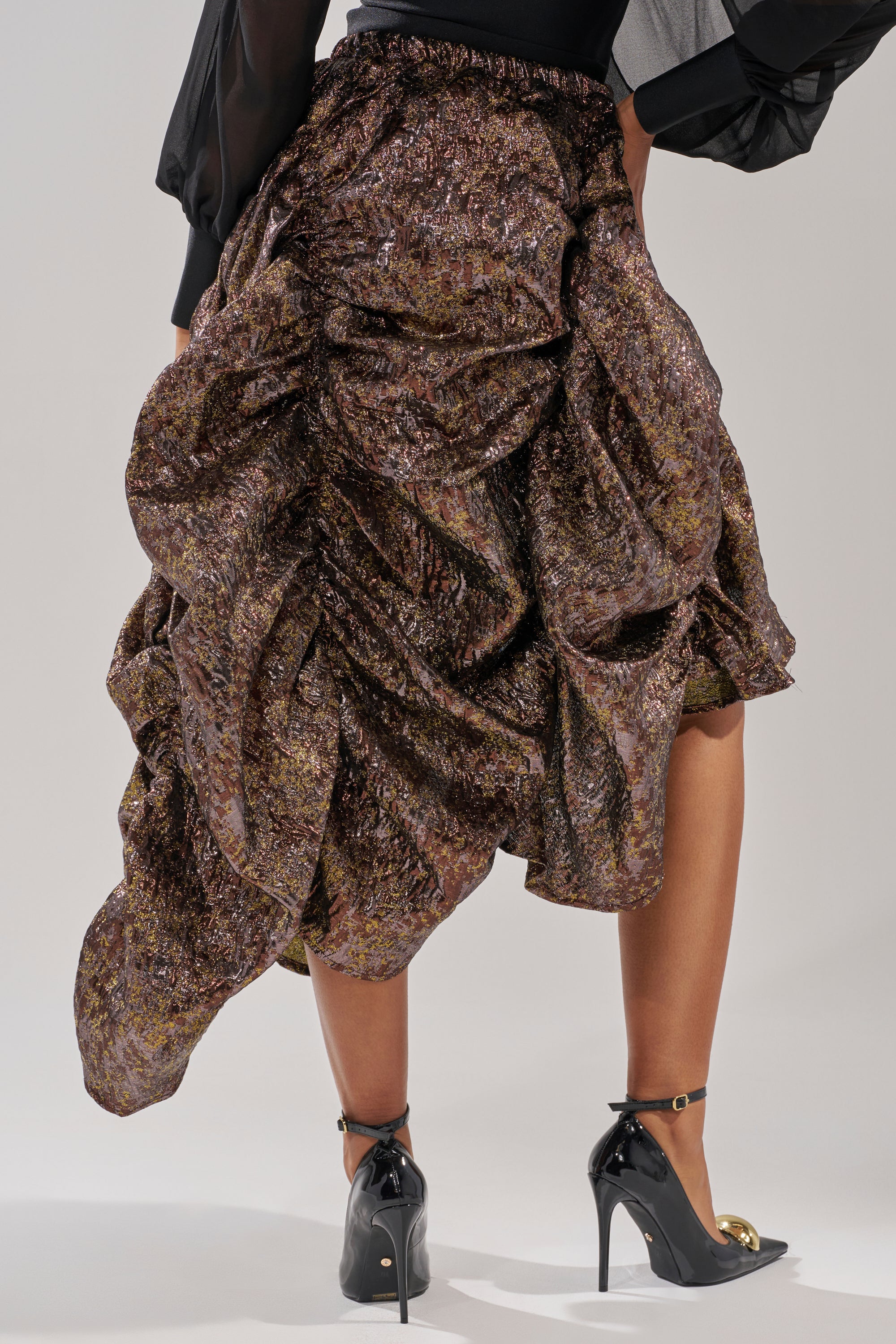 A person wears the CRAZY FOR YOU BROCADE RUCHED MIDI SKIRT and black high heels with gold ankle straps, shown from the back against a plain background. 5