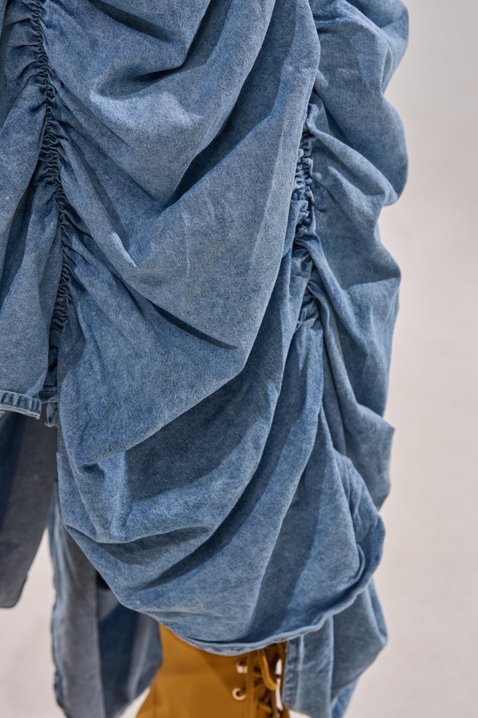 A close-up of blue fabric showcasing the soft texture found on the LETS CHANGE IT UP RUCHED MIDI SKIRT IN CHAMBRAY. 10