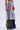 Wearing the SEE YOU NEXT TUESDAY PANT—grey sweatpants with black stripes, a red patch, and camo-patterned plus denim layers—a person stands against a plain light background.