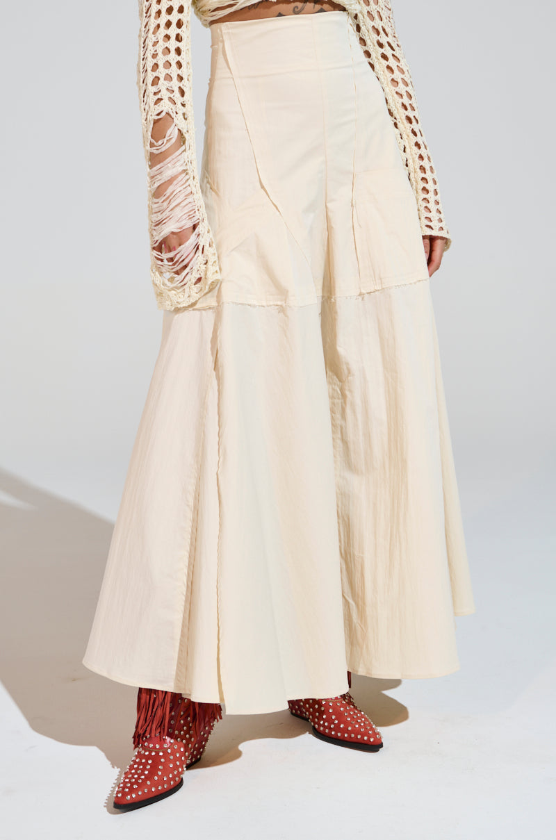 Someone in a cream CLAIRE EXPOSED SEAMS MIDI SKIRT paired with a textured long-sleeve top, red ankle boots adorned with white polka dots and fringe detail. The photo features a plain background. 3