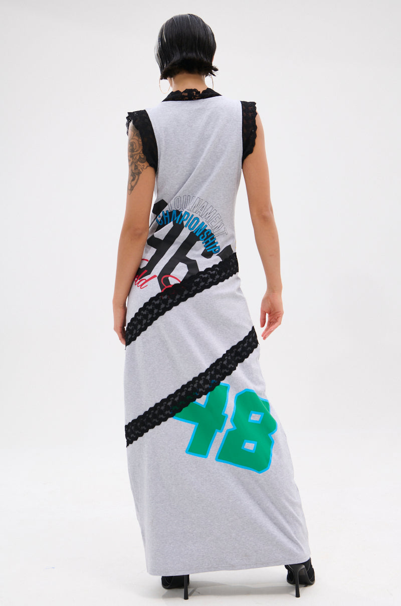 A person with short dark hair stands facing away, wearing the INSTA SAW IT FIRST GRAPHIC MAXI DRESS featuring black lace trim, sporty graphics, red text, and a large teal number 48 on the lower back.