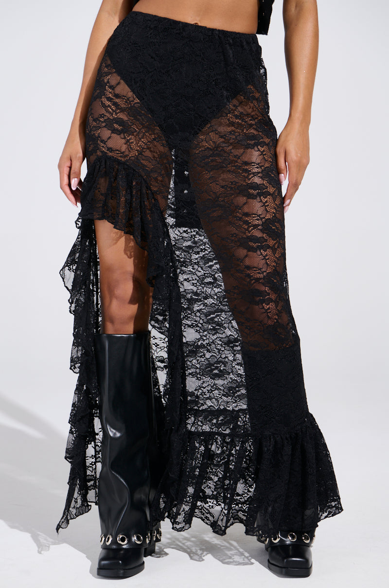 A person models the DANCE THE NIGHT AWAY LACE MAXI SKIRT, pairing it with knee-high black boots adorned with metal eyelets. This stylish and edgy ensemble is perfect for a festival-ready look against a plain white backdrop.