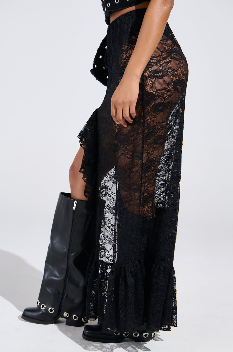 Wearing the "Dance The Night Away" lace maxi skirt, complete with a sheer floral design, ruffled hem, and side slit, paired with tall black boots adorned with eyelet details for a perfect festival-ready look.