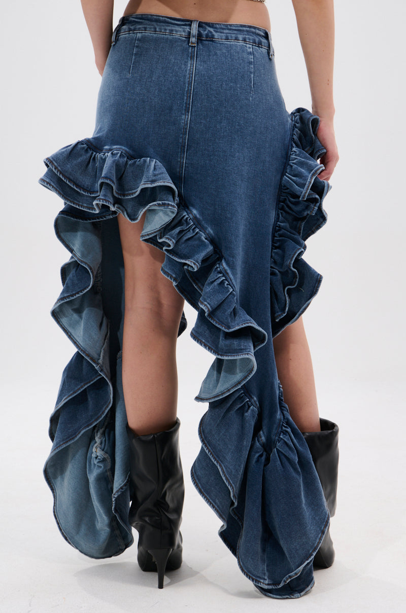 Wearing the DONT MESS WITH MY HEART DENIM RUFFLE SKIRT, which features dramatic ruffles at the back and sides, paired with black heeled boots. Captured from behind against a neutral backdrop for bold street-style denim vibes.