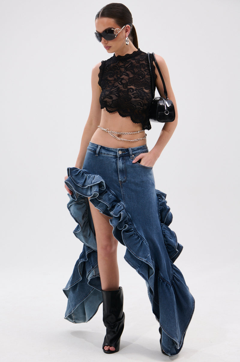 A woman poses in the DONT MESS WITH MY HEART DENIM RUFFLE SKIRT styled with a black lace crop top, high-slit design, black peep-toe boots, chain belt, sunglasses, earrings, and a small black shoulder bag.