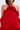 A woman stuns in the CHIC AF RUFFLE MINI DRESS IN RED, featuring a halter neckline, ruffles, bold rose neck detail, lustrous satin fabric, bare shoulders, and matching red detached sleeves.