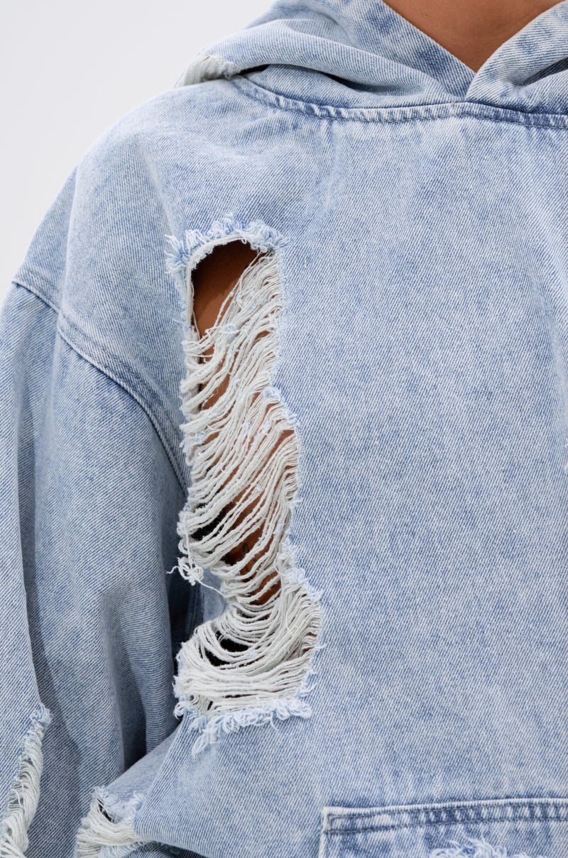 Close-up of the TRINITY DISTRESSED DENIM HOODIE in an oversized, light-wash style, featuring a large frayed rip on the upper sleeve, a smaller rip near the pocket, and raw edges that highlight its worn texture.