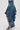A person wears the CRAZY FOR YOU DENIM SKIRT with a distressed hem, layered ruffled asymmetrical panels, high-low silhouette, and pairs it with matching denim high-heeled sandals for a standout look.