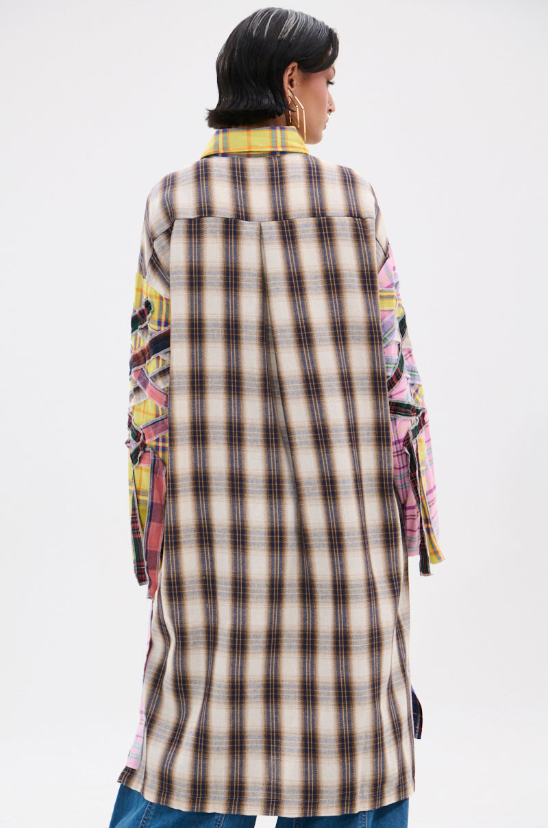 A person with short dark hair is seen from behind wearing the DONT EVEN MIXED PLAID LONG BUTTON DOWN, an oversized flannel shirt with mixed brown, yellow, pink, and green plaid patterns, set against a plain white background.