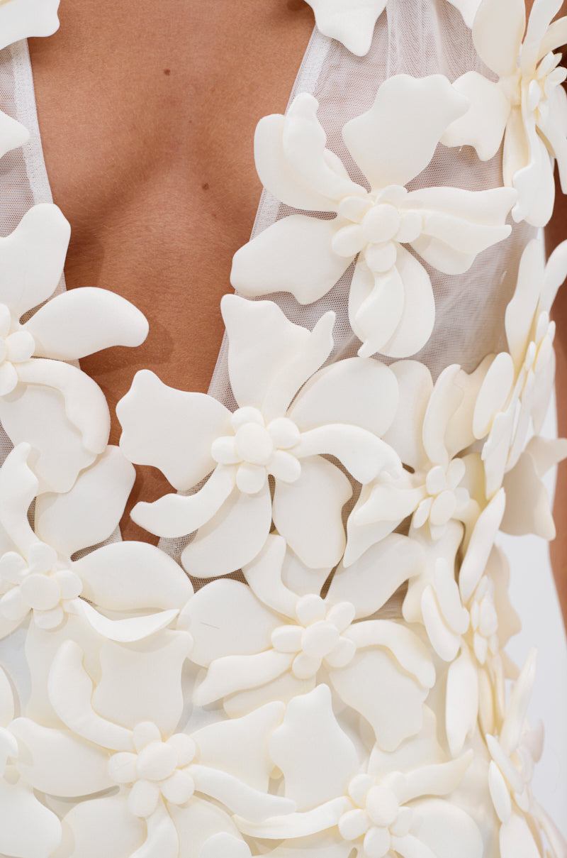 Close-up of the ASHLEY FLORAL MINI DRESS IN WHITE, adorned with bold 3D floral appliques and a sheer, plunging neckline—ideal for an elegant garden party look.