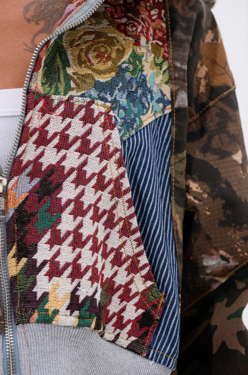 Close-up of the WILD AND FREE ZIP UP SWEATSHIRT, a patchwork hoodie with floral, houndstooth, striped, and camo denim patterns, partially unzipped to show a white inner layer. 9