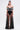 A woman with long hair models the MARA SHEER POLKA DOT MAXI SKIRT over high-waisted black briefs, paired with an off-the-shoulder striped top, gold earrings, and a cuff bracelet against a white background for a Parisian-inspired look.