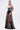 A woman wears the MARA SHEER POLKA DOT MAXI SKIRT with black underwear, pairing it with a black and white off-shoulder striped top. Her hair is pulled back and she accessorizes with a gold bracelet and earrings for a Parisian fashion-inspired look.