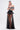 A woman exudes confidence in the MARA SHEER POLKA DOT MAXI SKIRT, pairing it with a striking black and white off-the-shoulder top and unique cage hip detail, channeling Parisian style against a clean white backdrop.