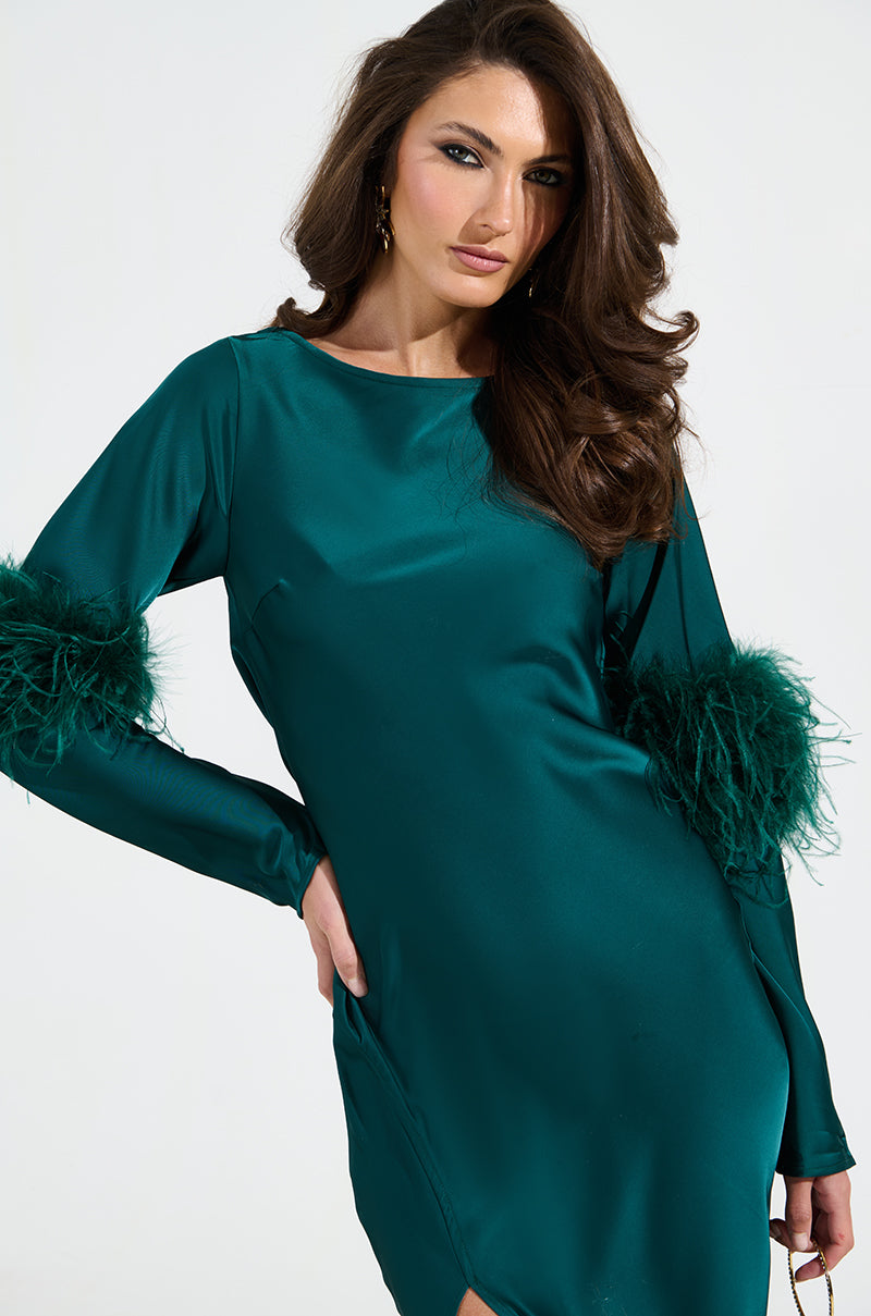A woman confidently poses in a glamorous CARRIE FEATHER SLEEVE MAXI DRESS, showcasing its mermaid silhouette and satin fabric. Her long brown hair cascades beautifully against a plain white background.