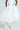 Posing with arms on their hips, the person dons THE BEST MAXI BUBBLE SKIRT paired with a fitted top and white high-heeled boots against a simple, light-colored background.