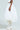 Someone wearing "THE BEST MAXI BUBBLE SKIRT," voluminous and white, paired with tall, uniquely structured white boots. The side view against a light background accentuates the flowing midi-length of the skirt and intricate boot design.