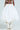 Someone is wearing THE BEST MAXI BUBBLE SKIRT in white, showcasing its voluminous, puffy design from the back. It’s paired with knee-high lace-up white boots on a plain background.