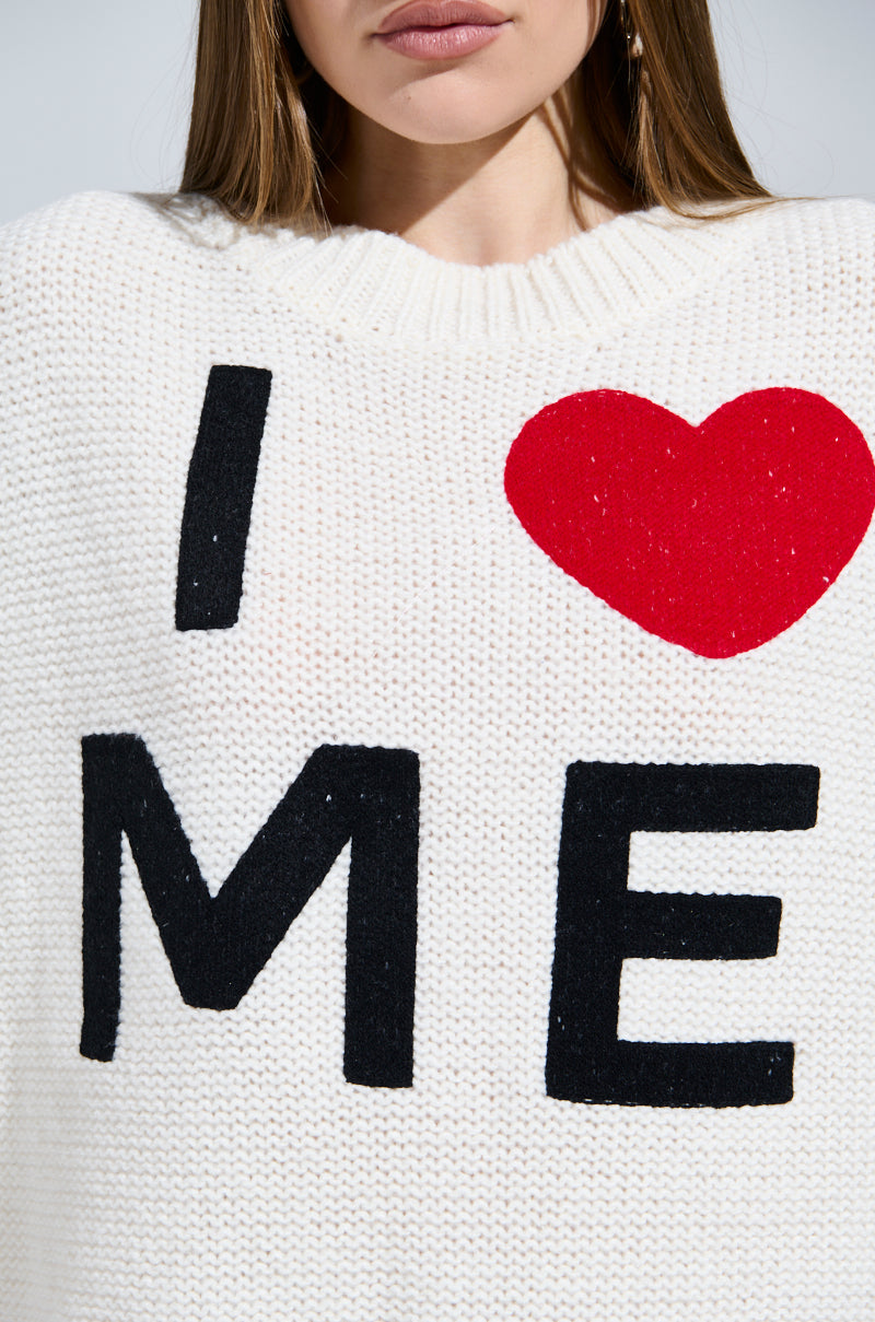 A person wears a LOVE MYSELF PRINTED SWEATER DRESS in cozy-chic cream, featuring "I ❤️ ME" bold lettering in black and red. The focus is on the message while their face is partially visible, adding intrigue to this self-love masterpiece.