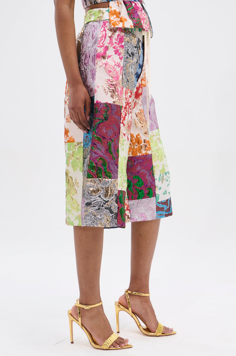 A person is wearing colorful MIXED FEELINGS BROCADE BERMUDA SHORTs with a high-rise waistband. They pair it with gold high-heeled sandals featuring ankle straps, all set against a plain white background.