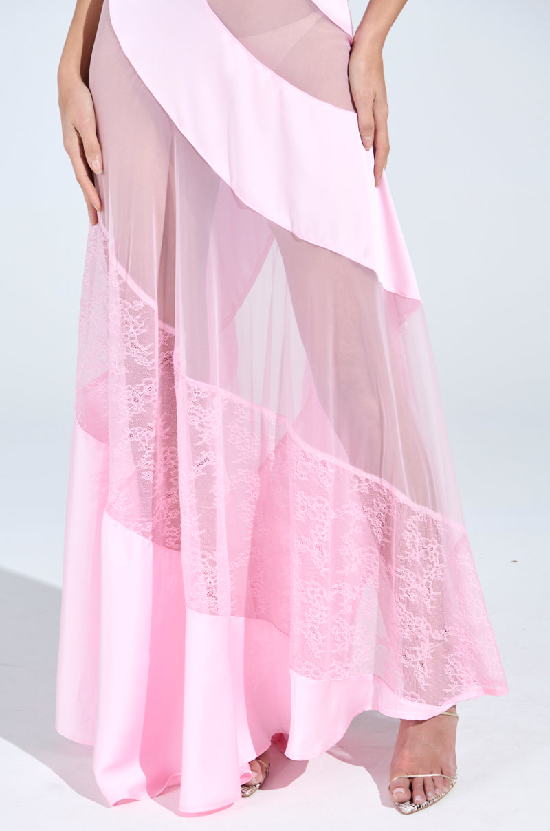 A person wearing the elegant ISABELLA SATIN MAXI DRESS, featuring sheer, flowing pink fabric with layered floral lace details, showcases their foot in a clear high heel against a plain light backdrop.