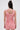 A woman with straight, dark brown hair in a half-up bun stands with her back to the camera, wearing the LEXI FLORAL MINI DRESS—a light pink mini dress with a curve-hugging fit and visible back zipper—against a plain light background.