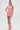 A woman poses against a white background in the LEXI FLORAL MINI DRESS, featuring 3D floral appliqués and a curve-hugging fit. She pairs it with pink heels, straight long hair, and elegant long earrings.