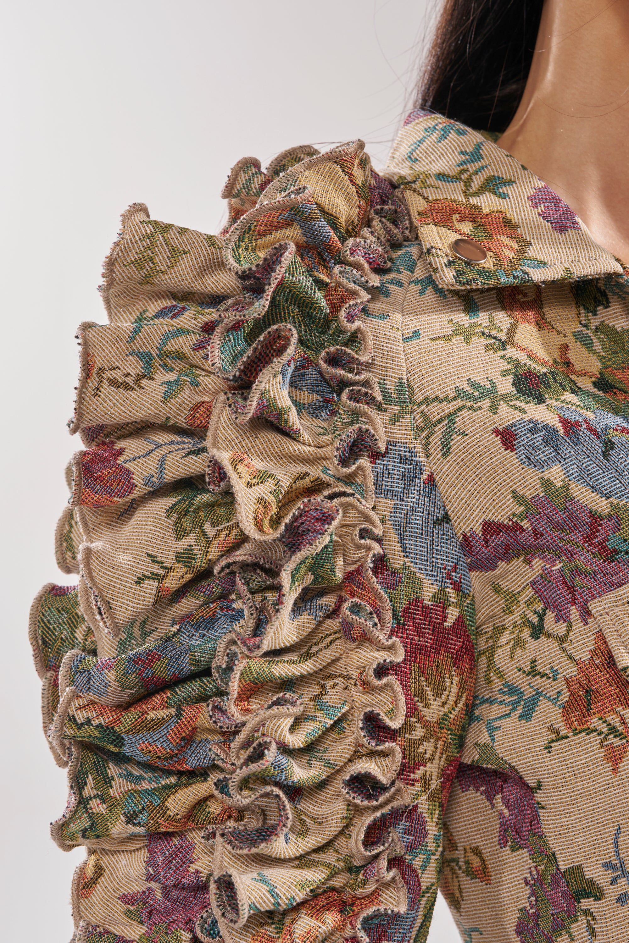 A close-up of the MAKE IT LOOK EASY TAPESTRY MOTO jacket showcases its ruffled sleeve and textured detailing. 12