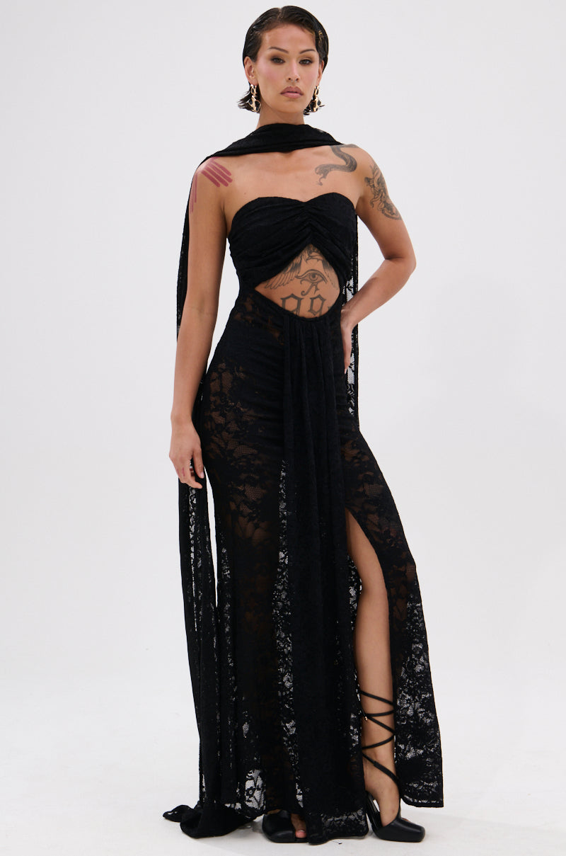Confident in the READY FOR A NIGHT OUT LACE MAXI DRESS, a person showcases tattoos and statement earrings. The sheer strapless maxi features a high slit, cutouts, and comes with a matching scarf, styled with black lace-up shoes.