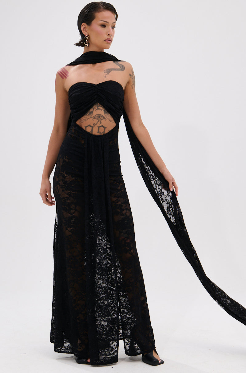 A person with short dark hair and visible tattoos models the READY FOR A NIGHT OUT LACE MAXI DRESS, a strapless sheer lace maxi with a chest cutout and matching long scarf, standing against a plain white background.