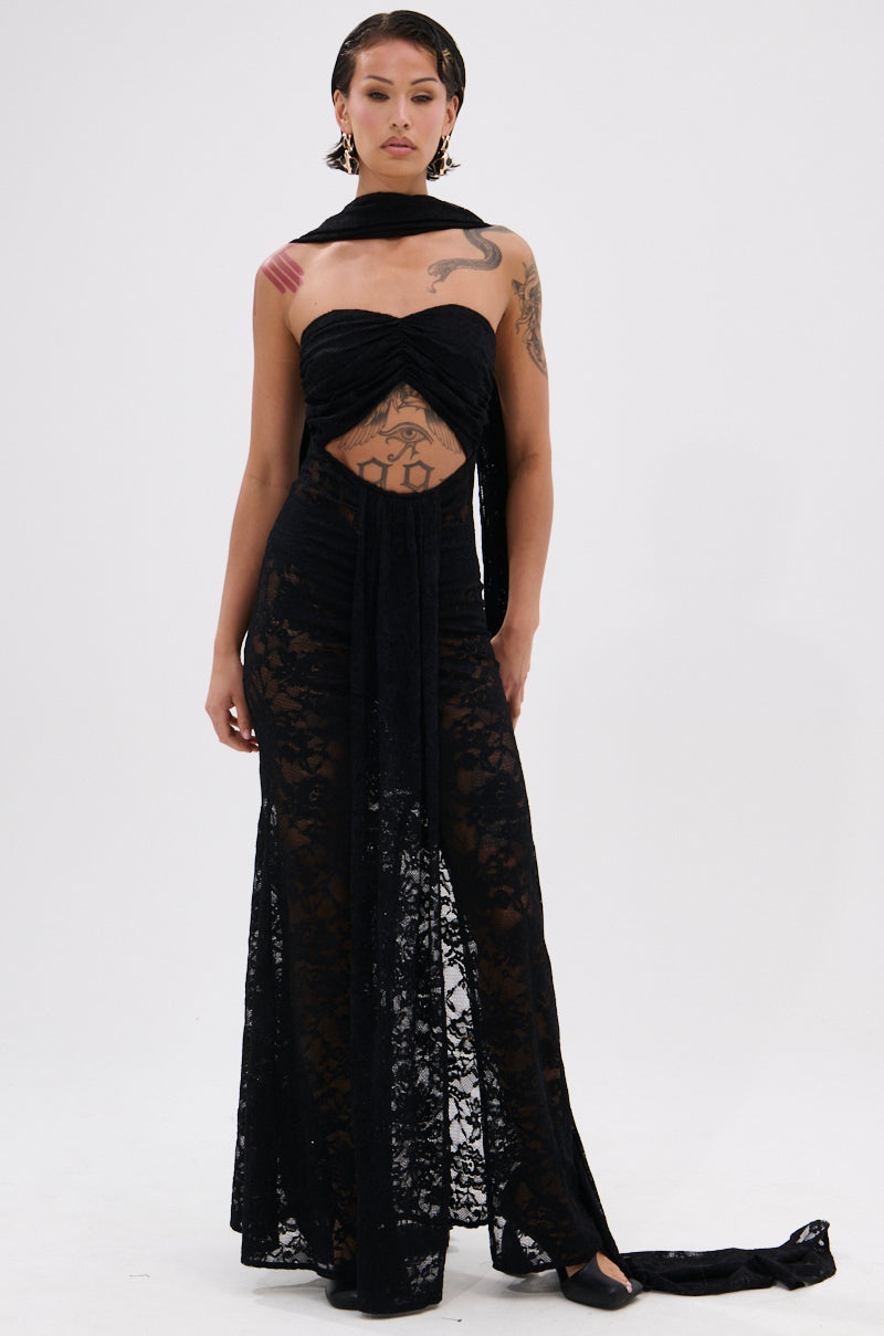 A tattooed woman models the READY FOR A NIGHT OUT LACE MAXI DRESS, a strapless sheer lace maxi with a midriff cutout and matching scarf. She stands against a white background, gazing confidently at the camera.
