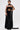 A woman poses confidently against a white background in the READY FOR A NIGHT OUT LACE MAXI DRESS, featuring a strapless design, sheer lace skirt, and cut-out midsection. She accessorizes with statement earrings and a long black scarf.