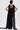 A person with short dark hair and visible back tattoos models the READY FOR A NIGHT OUT LACE MAXI DRESS with a matching draped scarf, standing against a plain white background and facing away from the camera.